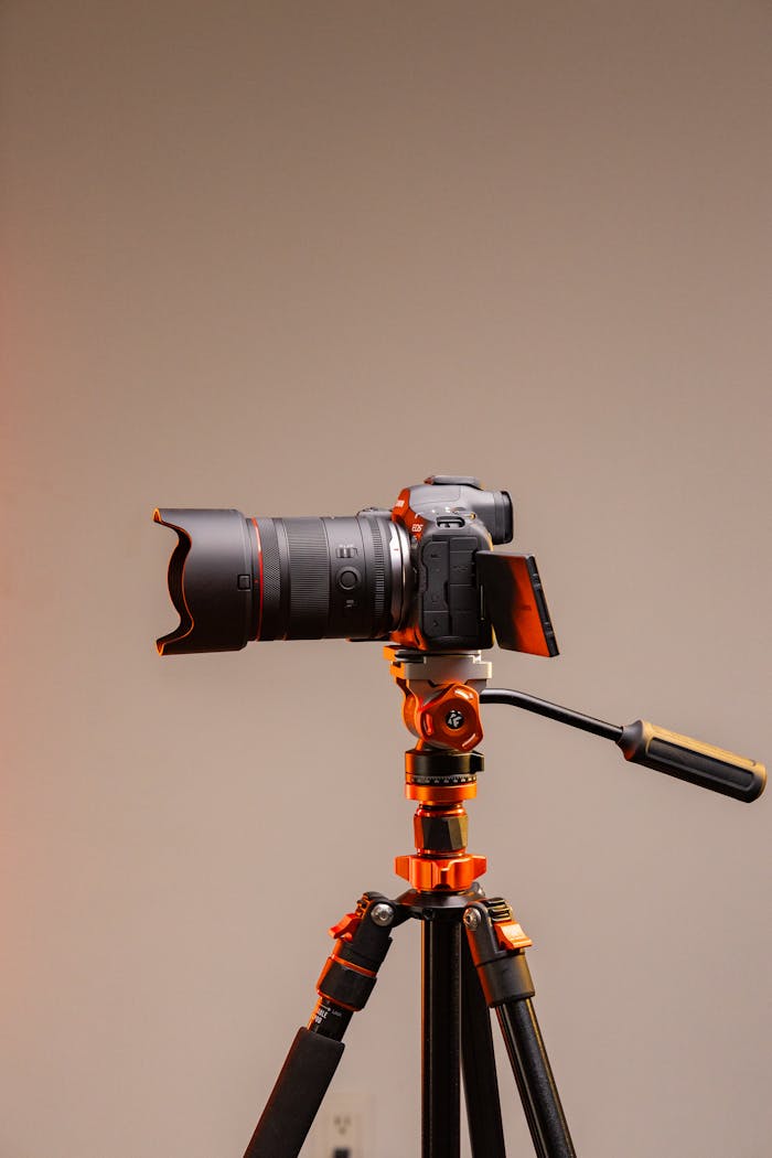 Studio shot of a modern camera on a tripod with orange lighting.